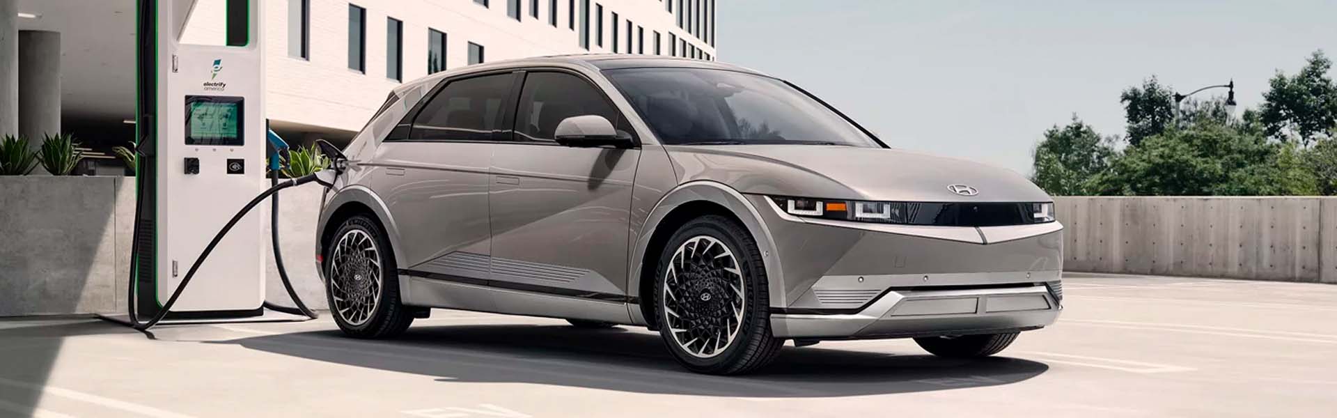 Gray Hyundai Ioniq parked in a parking lot next a big building on a sunny day